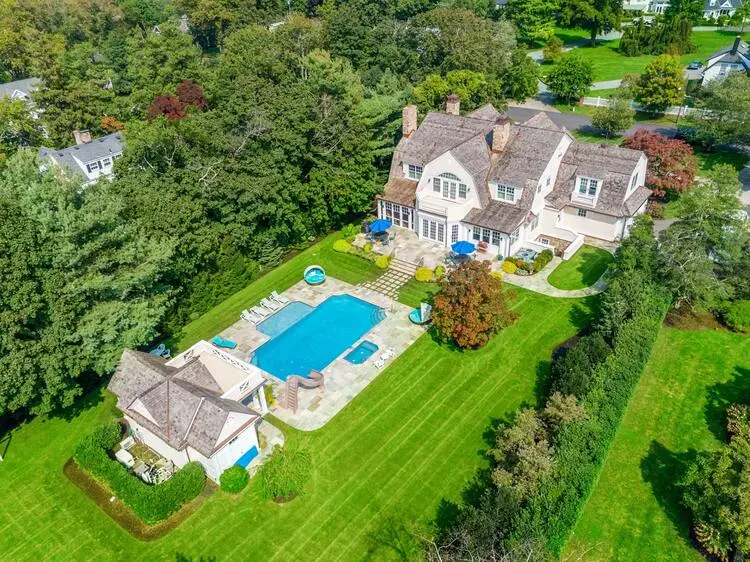 Aerial view of a luxurious mansion with a pool and pool house, showcasing opulent outdoor living.