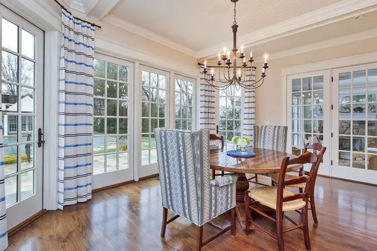 Dining room with large windows and hardwood floors, offering a bright and elegant space for meals.
